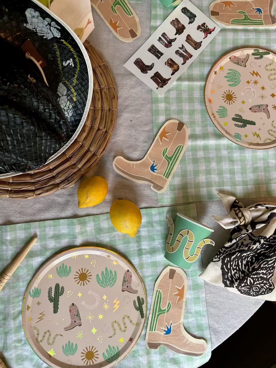 Cowboy boot temporary tattoos sheet with western-themed plates, cups, and decorations on a green checkered tablecloth