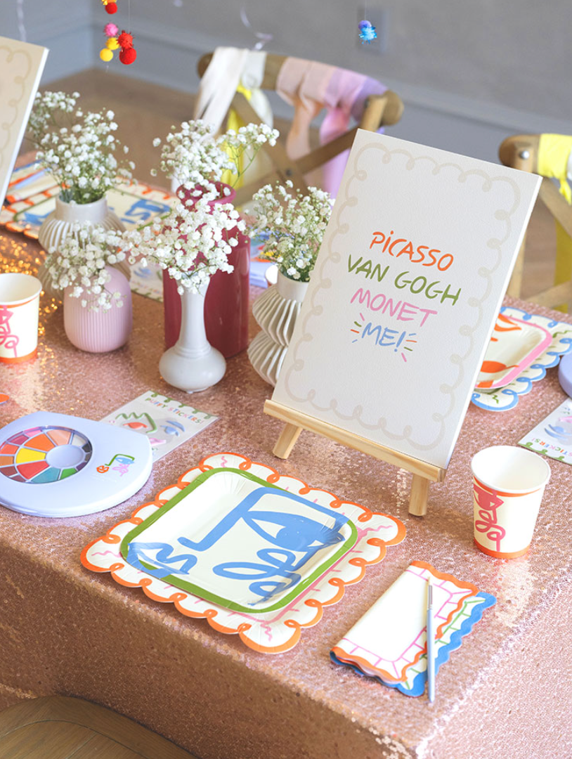 Children's art sparty set up with paper pad, plates, cups, and watercolors.
