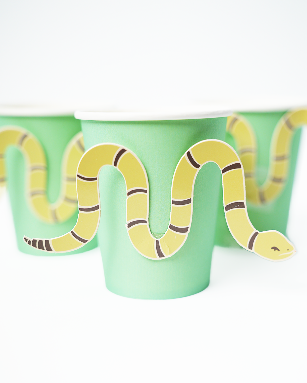 Green cowboy party cups with yellow snake stickers wrapping around each cup, 12-pack for western-themed events