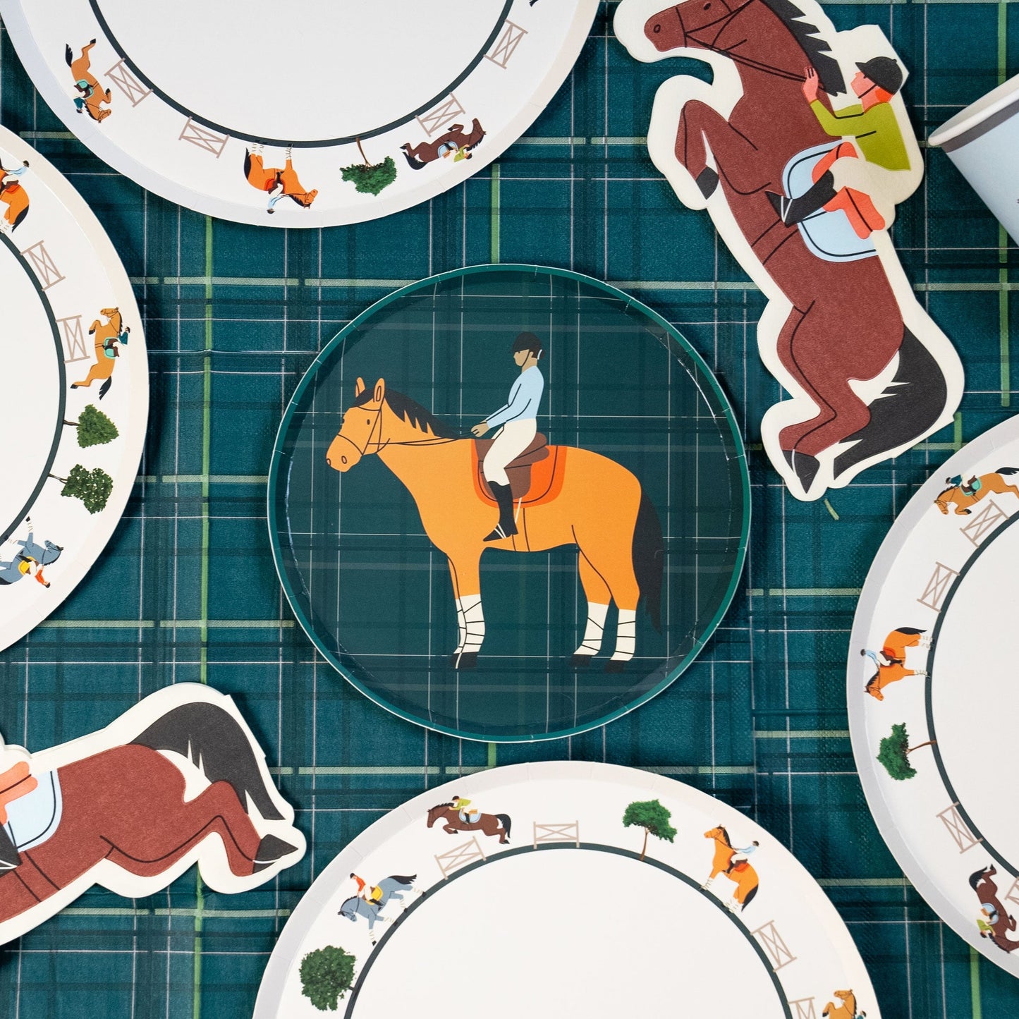 Horse party supplies set with dinner plates, dessert plates, cups, and napkins featuring horse and rider designs on plaid background