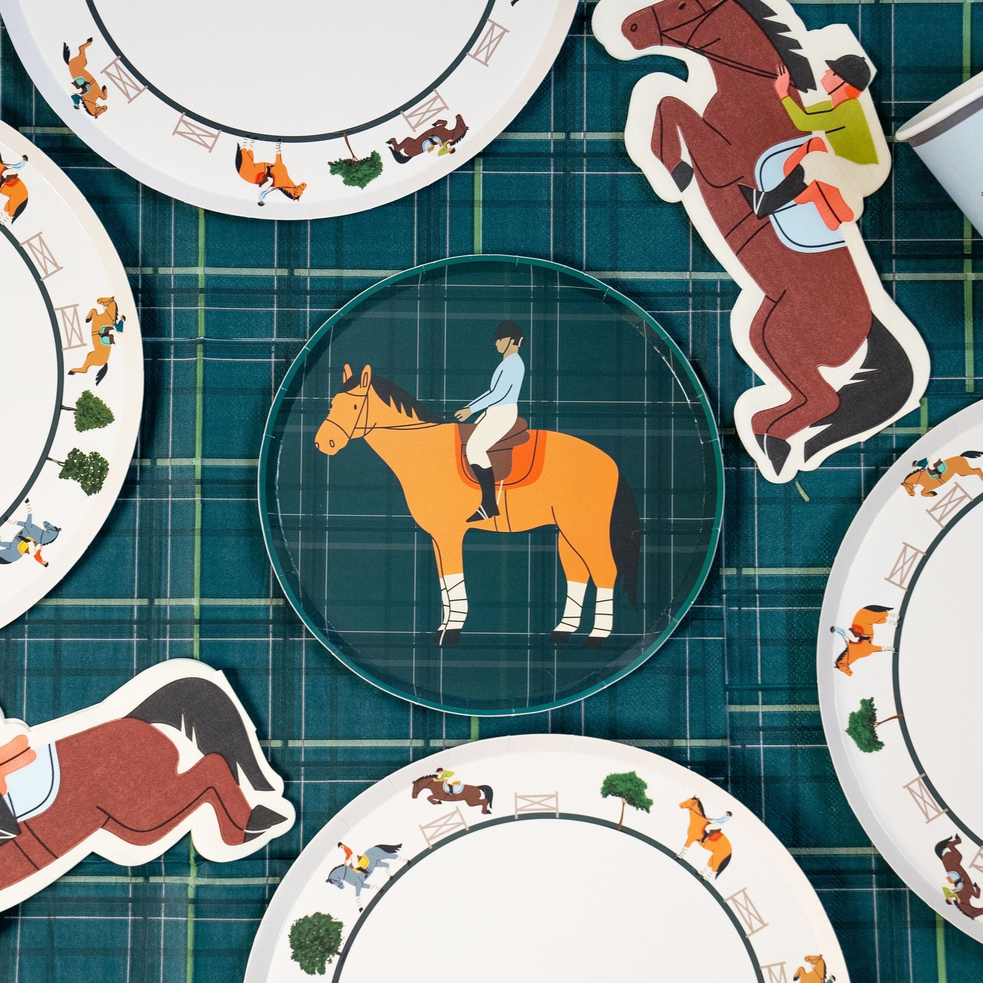 Horse party supplies set with dinner plates, dessert plates, cups, and napkins featuring horse and rider designs on plaid background